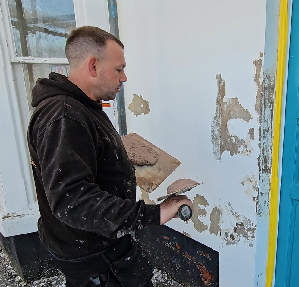 Cracked render being prepared before a spray cork coating is applied
